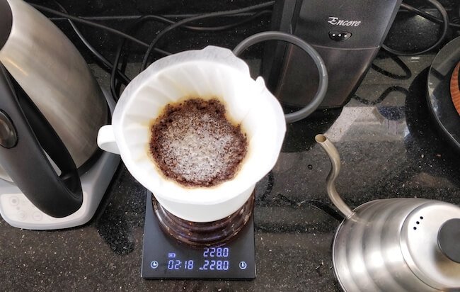 Professional barista demonstrating pour over coffee technique with V60 dripper vs cold brew brewing methods comparison